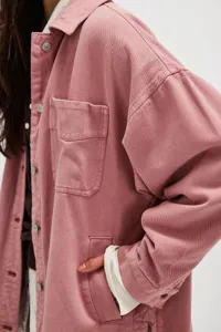 Close-up detail of women's pink denim jacket featuring chest pocket and classic lapel collar.