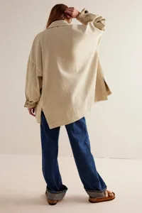 Back view detail of casual beige oversized side-split jacket paired with blue jeans.