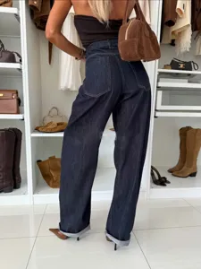 Detailed shot of dark blue wide-leg denim jeans featuring high waist and cuffed hems.