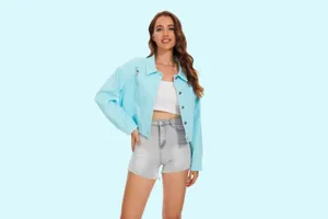 Gedetailleerd overzicht van het lichtblauwe versleten denim jasje gecombineerd met witte crop top.