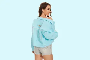 Gedetailleerd rugaanzicht van lichtblauwe denim damesjas met strass-franjes en scheuren.