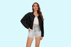 Detail van zwarte distressed denim jas met revers en knopen op een schone achtergrond.