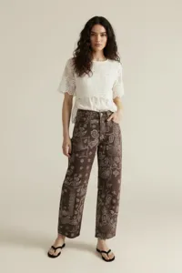Women's brown paisley print straight leg denim jeans paired with white lace short sleeve top.