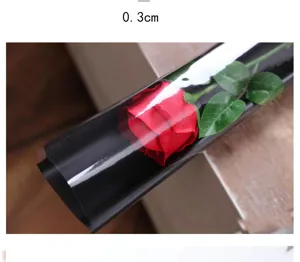 Artificial rose flower with green leaves wrapped in black transparent film for DIY crafts.