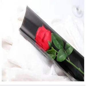 Single red artificial soap rose with green leaves and black wrapping paper for DIY gifts.