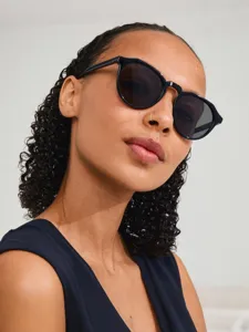 Klassieke zonnebril met een rond montuur en donkere glazen in vintage streetwear-stijl.