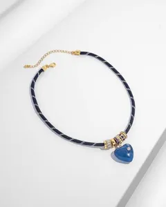 Detailansicht einer blauen Herz-Halskette mit dunkelblauem Seil und goldenen Akzenten.