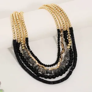 Primo piano di una collana multi-strato bohémien con perline dorate e pietre naturali