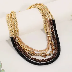 Primo piano di collana retrò multistrato con perline dorate e dettagli in pietra naturale.