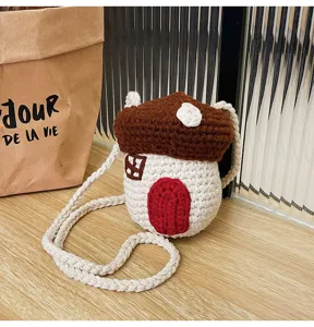Close-up of handmade crochet mushroom house crossbody bag on wooden table