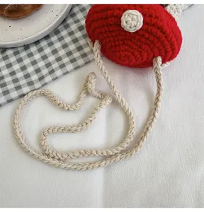 Detail view of a handmade red crochet mushroom crossbody bag with braided strap.