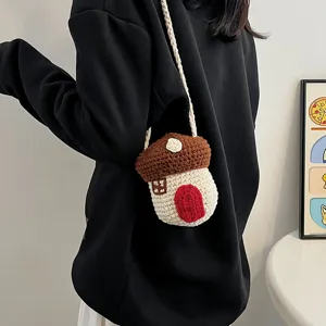 Handmade crochet mushroom house mini crossbody bag worn by a model in black hoodie
