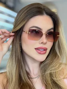 Lunettes de soleil carrées sans monture pour femme, verres dégradés et élégante monture dorée.