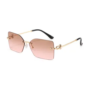 Lunettes de soleil carrées sans monture pour femme avec verres dégradés marron et branches dorées.
