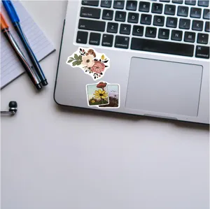 Detail shot of vintage botanical and illustration stickers applied on a modern laptop surface.