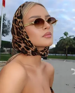 Gros plan détaillé de lunettes de soleil ovales en métal portées avec un foulard léopard.