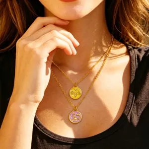 Layered gold chain necklace with zodiac coin pendants close-up shot showing enamel details.