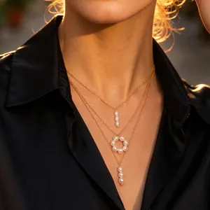 Detailed close-up shot of the layered gold chain necklace showcasing delicate white pearl pendants.