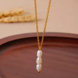 Detailed shot of a delicate gold-plated chain necklace featuring three vertical baroque pearls.