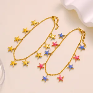 Detailopname van de gouden enkkelband met kleurrijke geëmailleerde sterhangers en fijn ketting.
