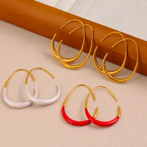 Gros plan de boucles d'oreilles géométriques en C, avec des designs bicolores or, blanc et rouge.
