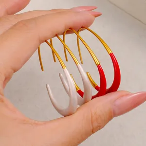 Gros plan de boucles d'oreilles créoles en C bicolores élégantes en or avec émail rouge et blanc.