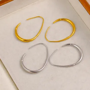Vue de détail de boucles d'oreilles créoles géométriques tendance en double ton or et argent.