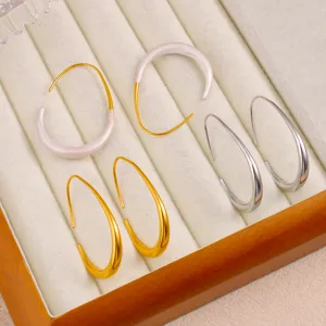 Gros plan détaillé de boucles d'oreilles géométriques en forme de C sur un plateau en velours.