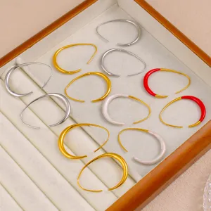 Détail de boucles d'oreilles créoles en C, design géométrique, acier titane multicolore.
