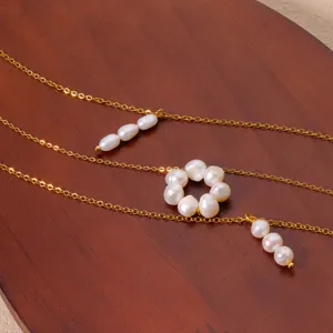 Close-up detail shot of dainty gold-plated chain necklace featuring delicate pearl flower and drop charms.