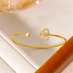Detailaufnahme eines 18K vergoldeten Armreifs mit Zirkonia-Herz und einzelnem Kristallstein.