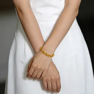 Close-up detail of a thick rope twist gold bracelet worn on wrist, elegant jewelry showcase.