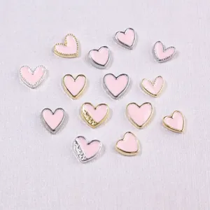 Close-up of pink heart nail art charms with gold and silver metal borders