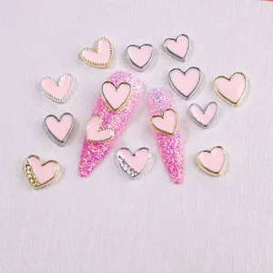 Close-up of pink enamel heart nail charms with gold and silver metal borders