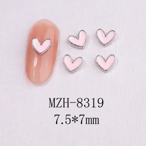 Close-up of pink enamel heart nail charms with silver metal edging on white background