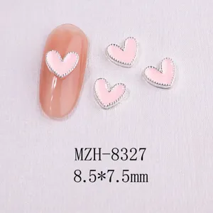 Close-up of pink enamel heart nail art charms with silver beaded metal edges.