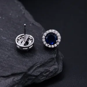 Klassieke ronde oorknopjes met blauwe edelsteen en sprankelende zirkonia halo stenen.