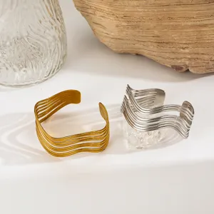 Detailed view of two multi-layered wavy open cuff bracelets in gold and silver finish