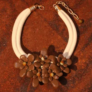 Detailed view of brown acrylic flower clusters on a beige cord double-layer necklace.