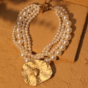 Collar de perlas multicapa con un colgante martillado en tono dorado