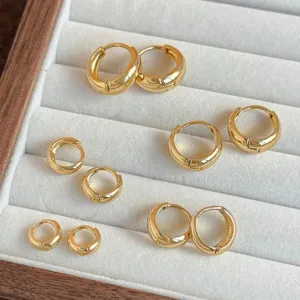 Close-up view of minimalist gold hoop earrings set, various sizes polished finish detail.