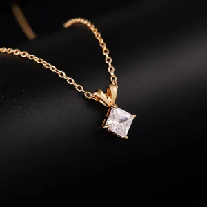 Close-up shot of a delicate gold chain necklace featuring a sparkling square cut pendant.