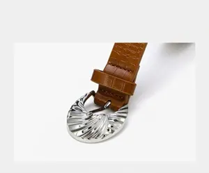 Detailed view of the women's brown embossed belt with a unique silver shell buckle.