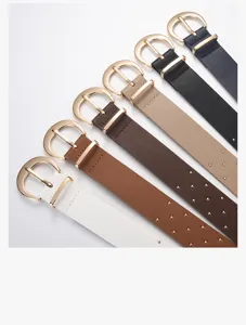 Gedetailleerd overzicht van brede lederen damesriemen met mooie gouden gespen en metalen studs.