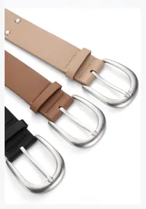 Close-up detail of stylish wide leather belts featuring metal buckles and rivet accents.