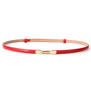 Close-up detail view of red patent leather slim belt featuring gold metal spring clasp.