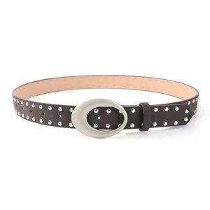 Close-up of the vintage brown suede studded belt showing metal rivets and large oval silver buckle.