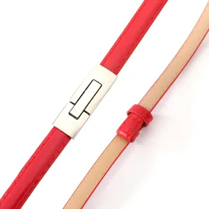 Detail view of red patent leather thin belt with silver interlocking buckle for women dress.