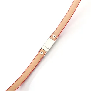 Detailed view of women's thin red patent leather belt with silver metal clasp and screws.