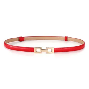 Close-up van de dunne rode lederen damesriem met gouden metalen sluitinggesp detail.